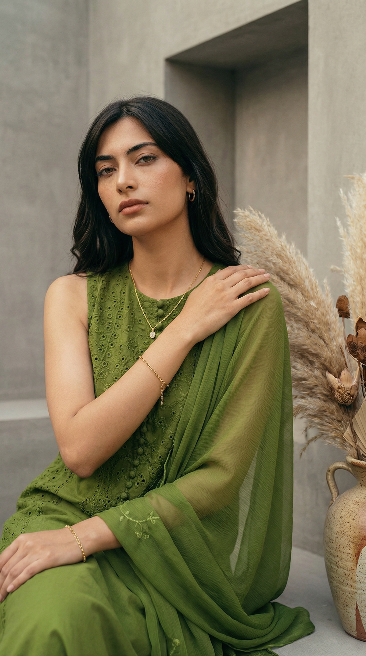 Woman in a green dress sitting against a neutral background