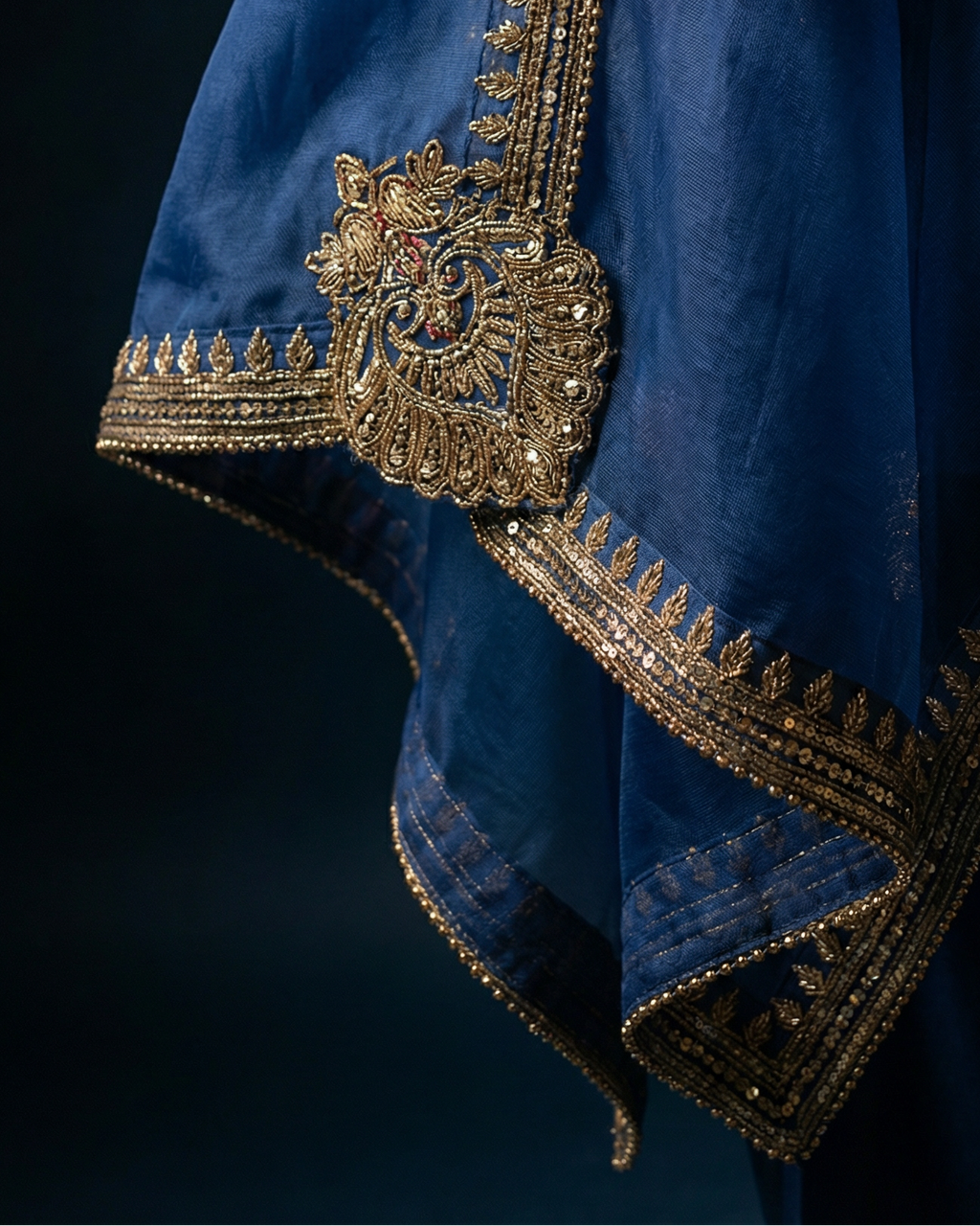 Blue fabric with intricate gold embroidery on a dark background