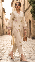 Woman in a cream traditional outfit walking down a stone street.